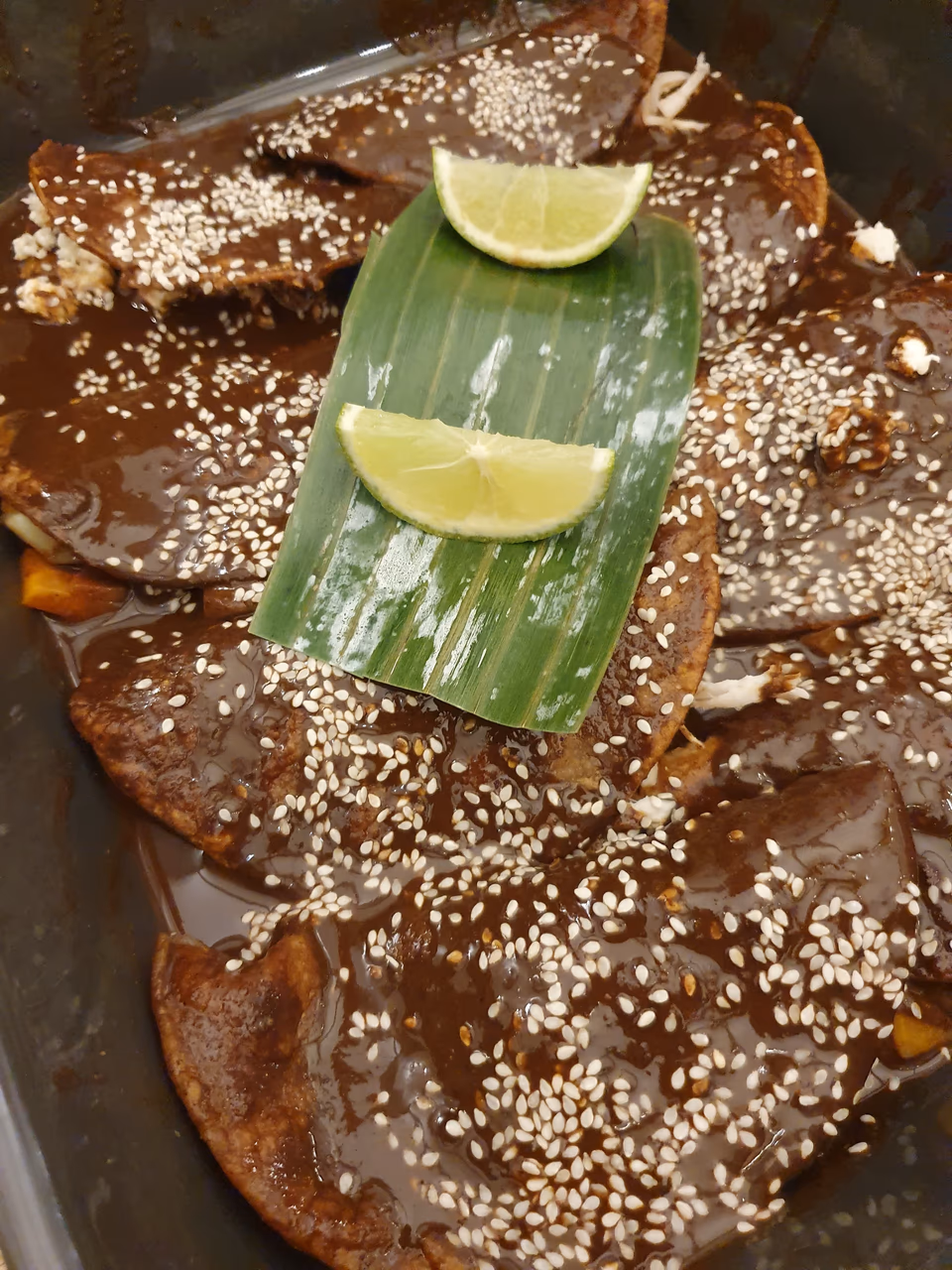 Mole mit Sesam und Limette auf einem Bananenblatt serviert