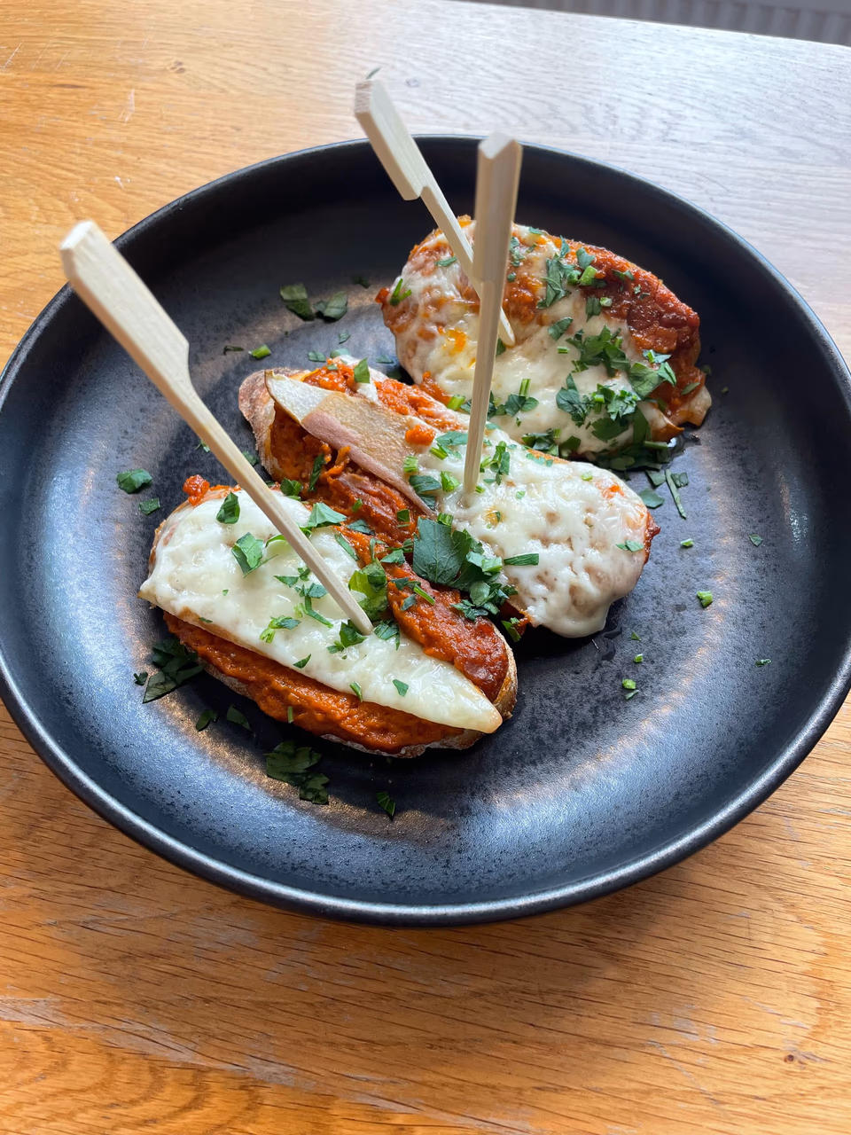 Pintxos mit Sauce und Kräutern auf einem dunklen Teller