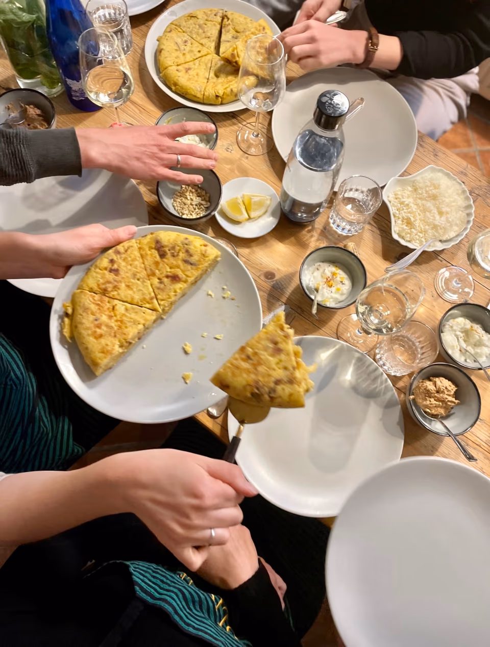 Tortilla Española am gedeckten Tisch, Gäste nehmen sich ein Stück