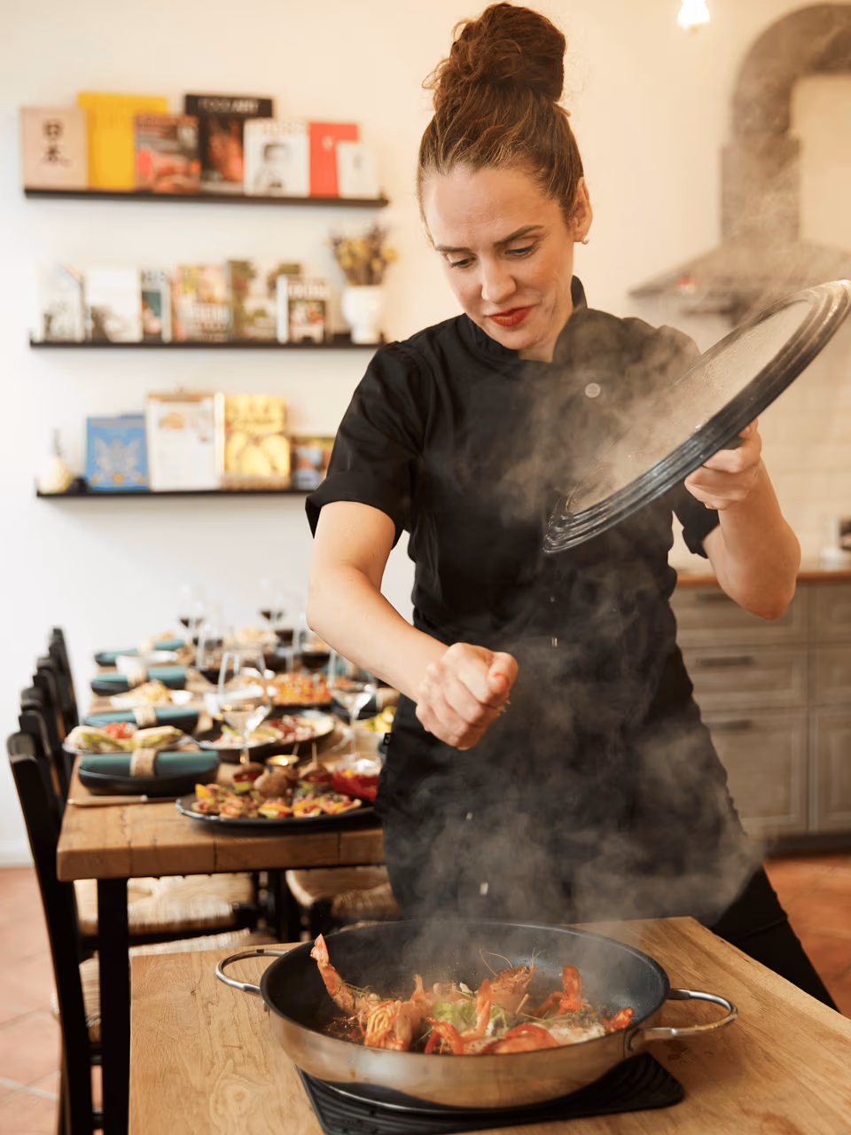 Köchin flambiert die Paella-Pfanne in der Kochschule