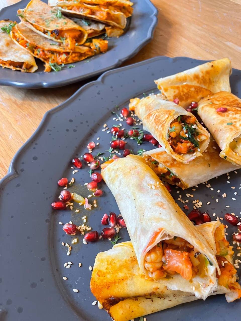 Gefüllte Tacos mit Granatapfelkernen auf einem dunklen Teller