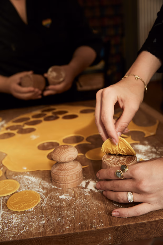 Zwei Paar Hände prägen Corzetti mit Holzstempeln
